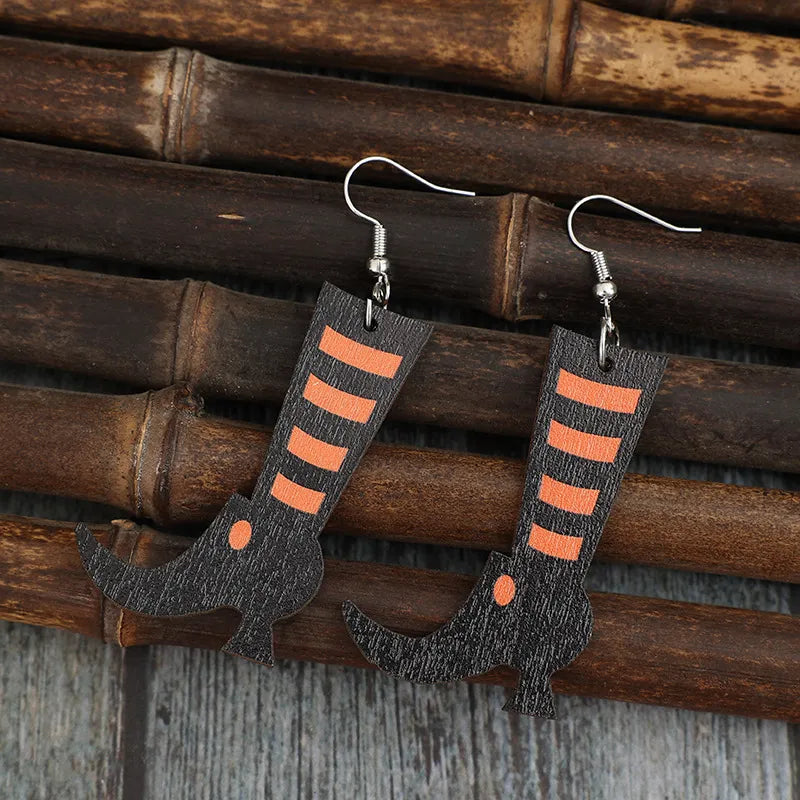 Black witch boot silhouette drop earrings with orange stripes and a small orange dot.