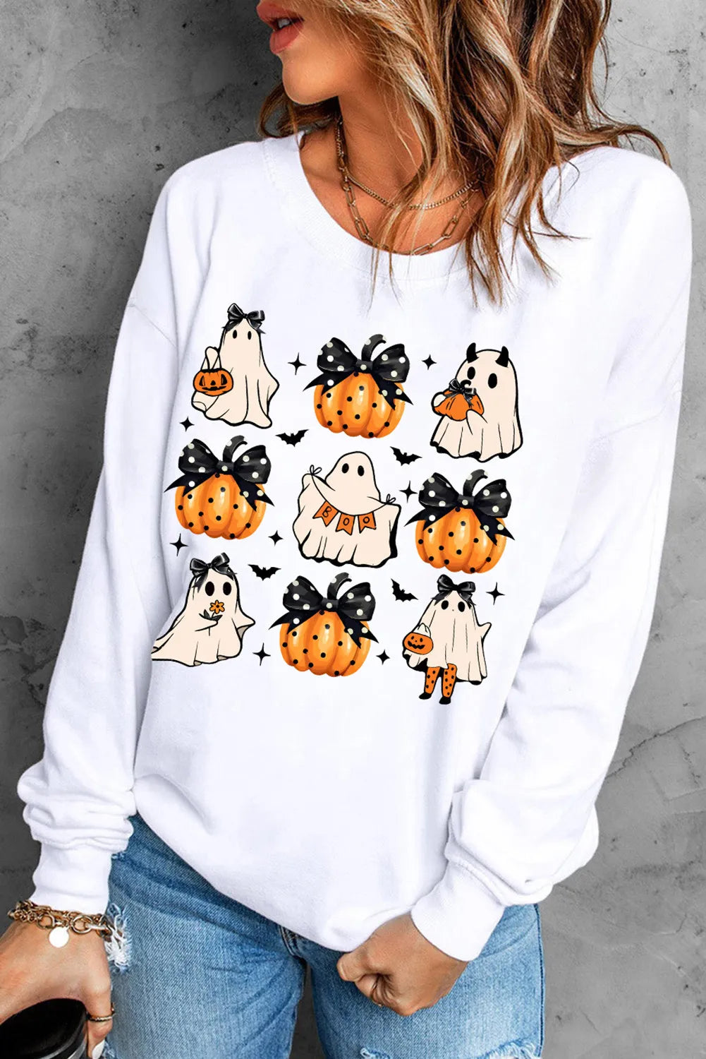 White sweatshirt with a spooky patchwork graphic of ghosts and pumpkins, perfect for autumn casual wear.