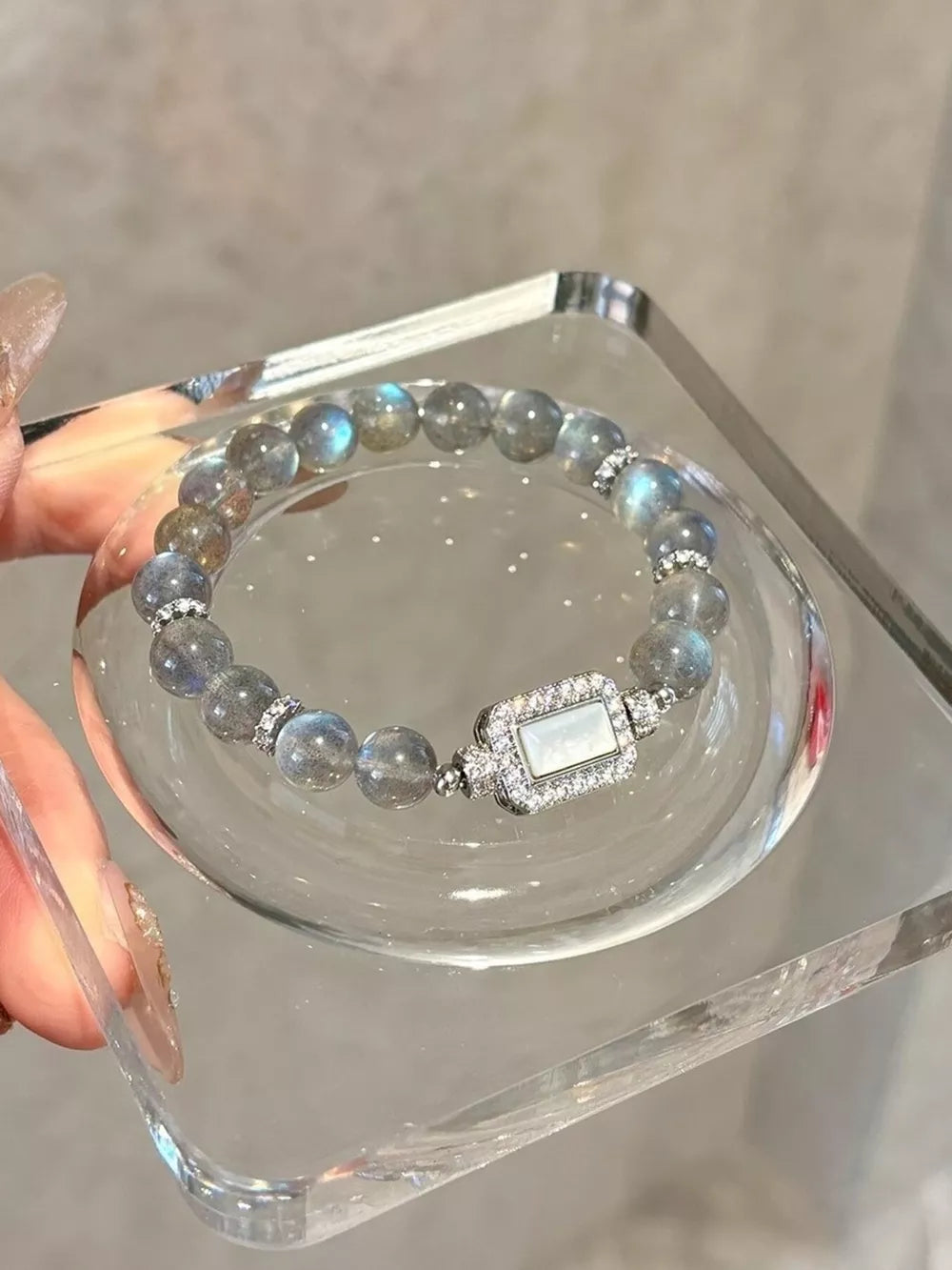 Iridescent moonstone beaded bracelet with a rectangular geometric clasp and crystal accents.