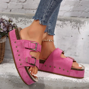 Hot pink platform slides with double buckles and stud detail.