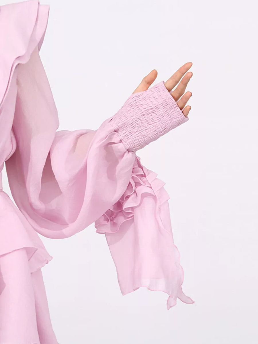 Pink tiered ruffle mini dress with smocked cuffs and flowing sleeves.