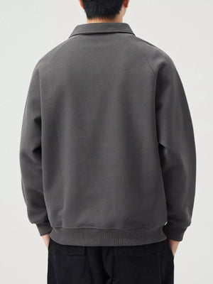 Dark gray raglan quarter zip sweatshirt with a collared neckline and ribbed cuffs and hem.