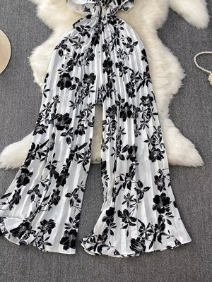 Black and white floral pleated wide-leg maternity romper with ruffled neckline.
