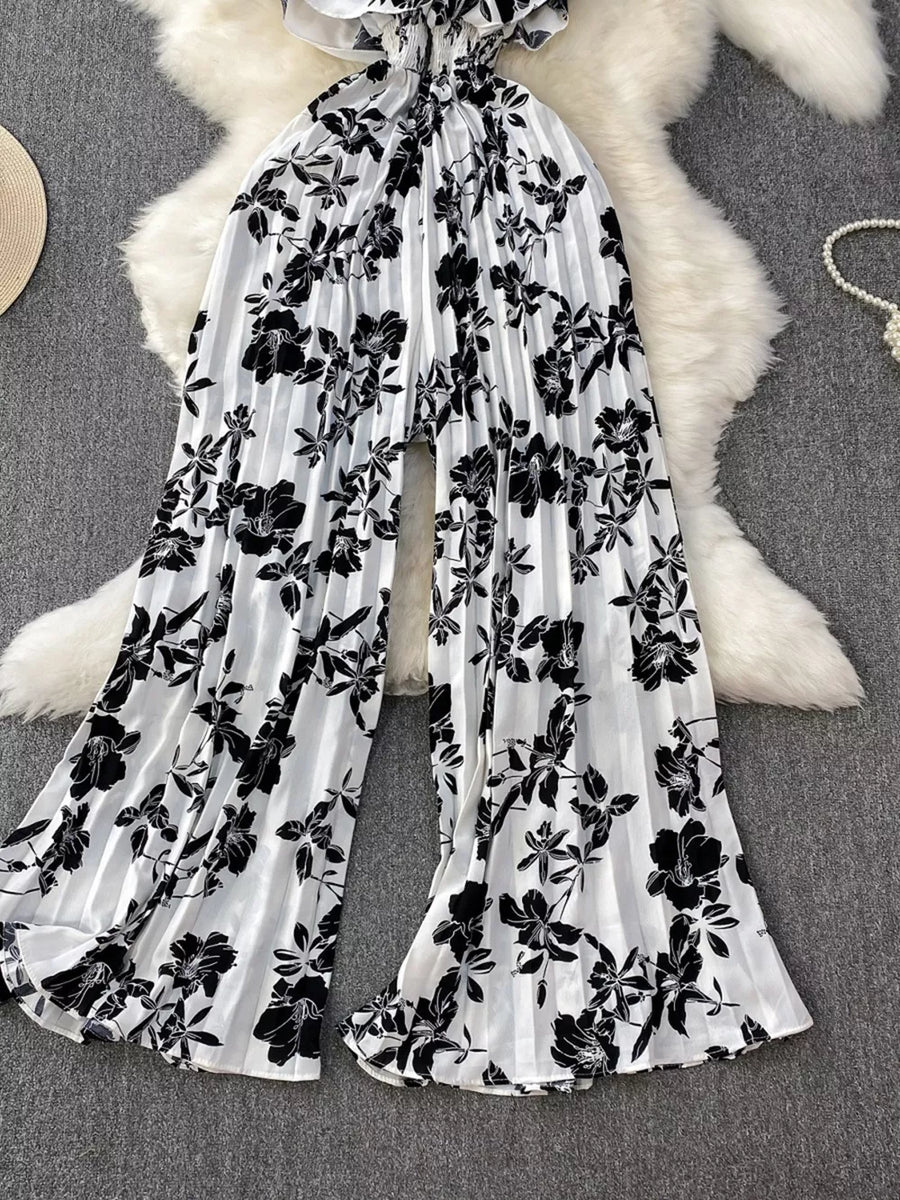 Black and white floral pleated wide-leg maternity romper with ruffled neckline.