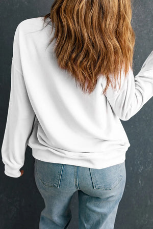 White crewneck sweatshirt with long sleeves and a relaxed fit, paired with blue jeans.