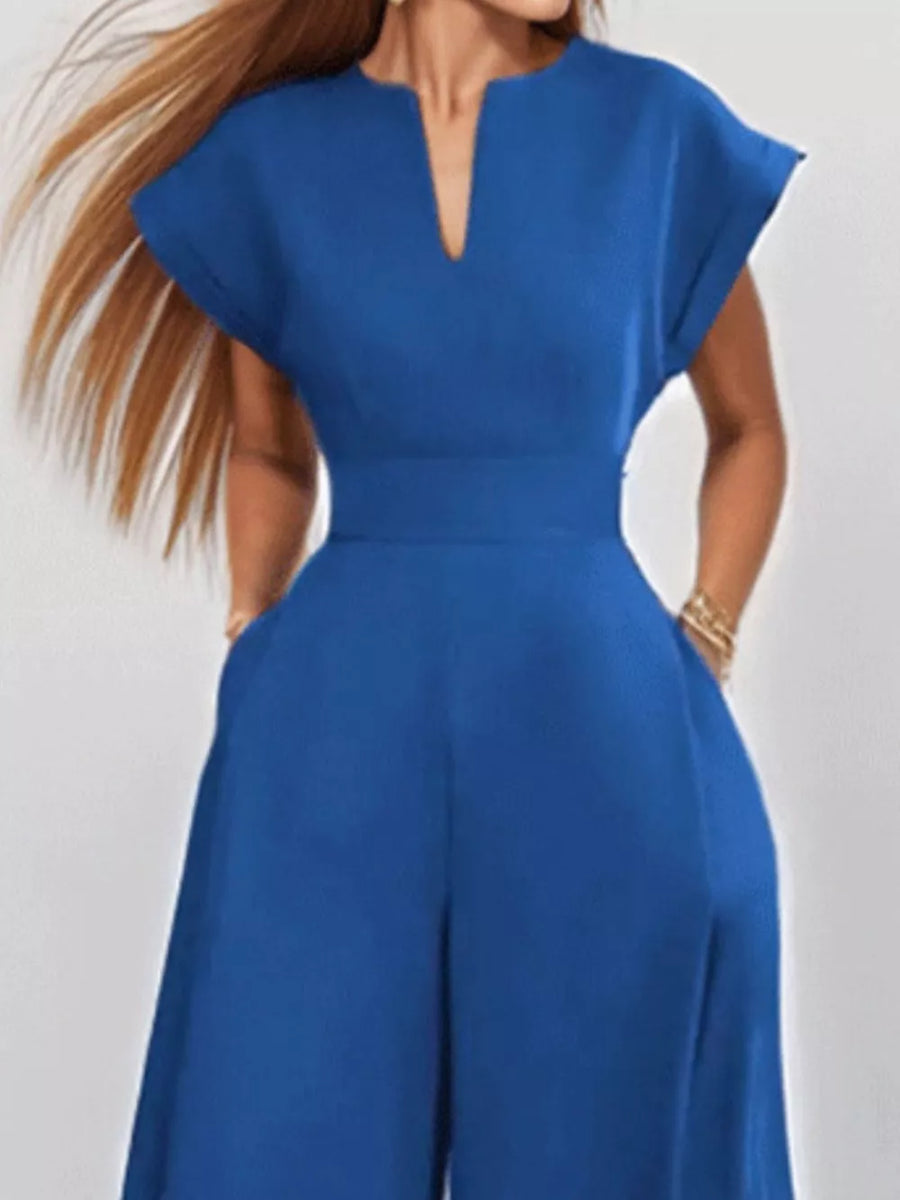 Navy wide-leg romper with V-neck, short sleeves, belted waist, and pockets.