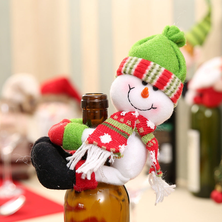 Holiday bottle topper with plush snowman, green hat, red & white striped scarf, and black pants.