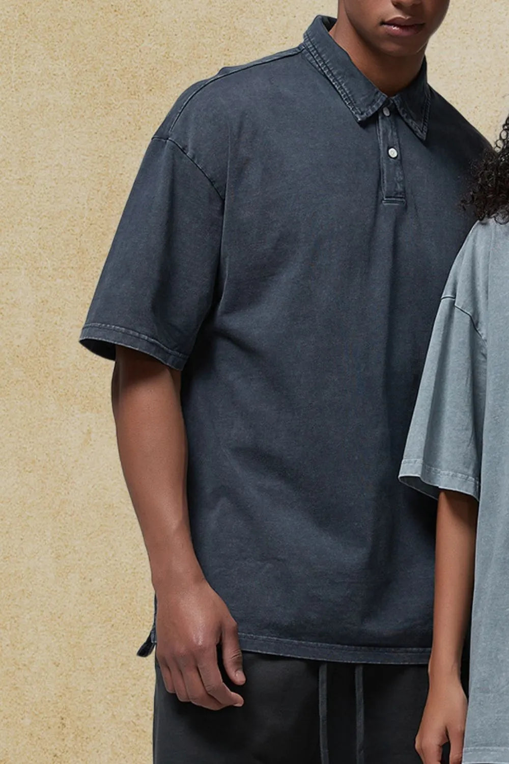 Oversized washed black polo shirt with short sleeves and a two-button placket.