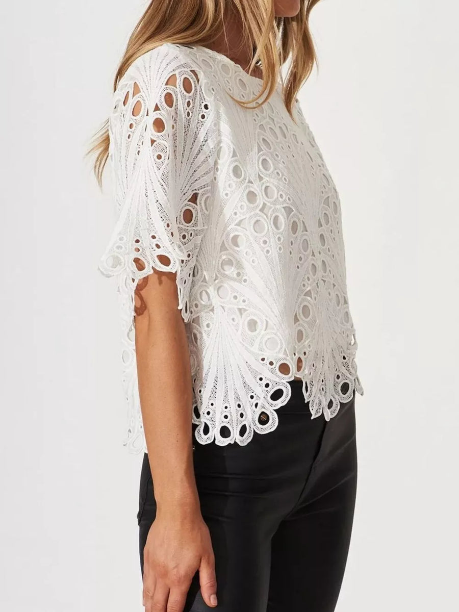White lace half-sleeve blouse with intricate eyelet pattern and scalloped hem.