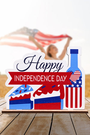 Patriotic wooden tabletop decor with "Happy Independence Day" text, cake slices, and a bottle with USA flag design.