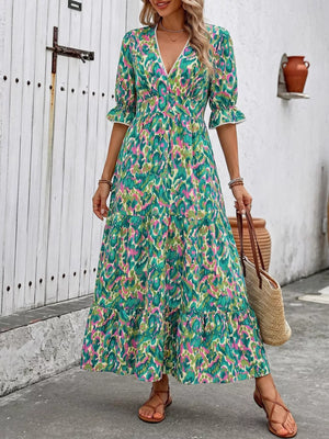 Vibrant V-neck maxi dress with abstract print, flounce sleeves, and tiered skirt.