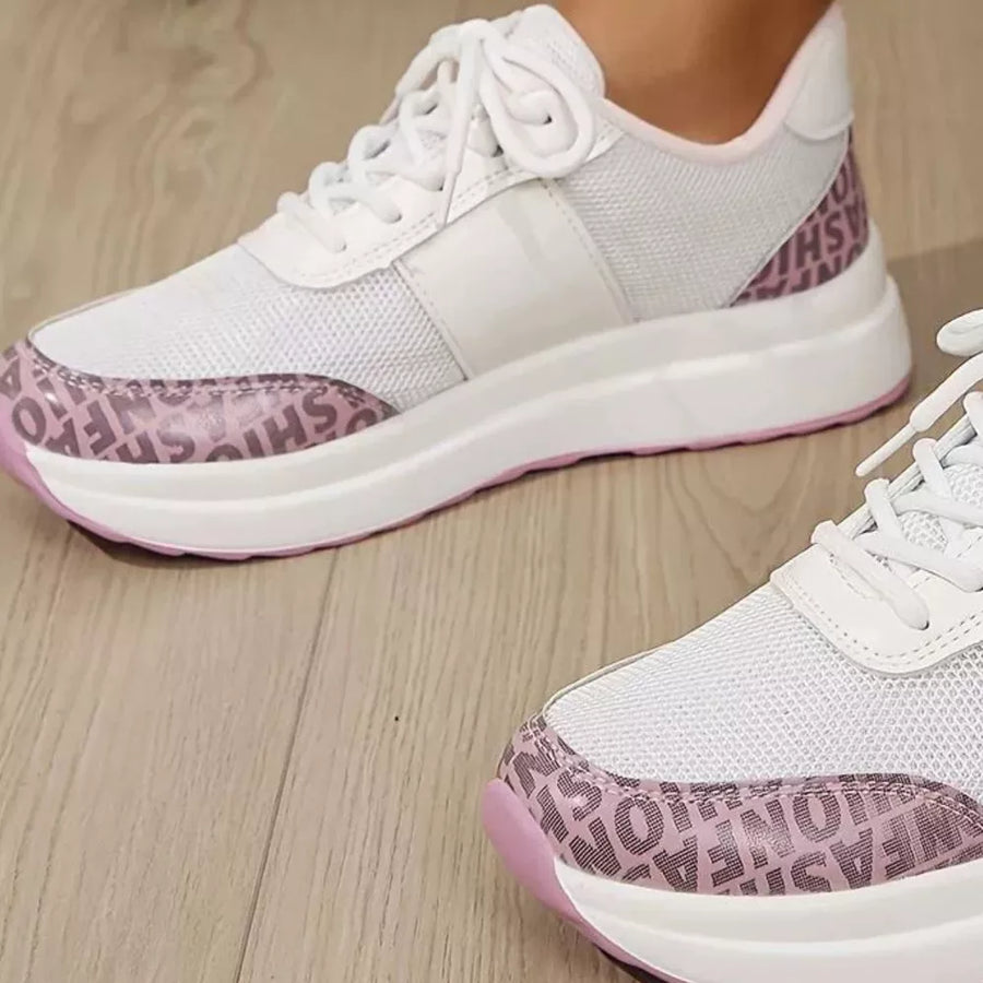 White lace-up sneakers with pink fashion print detailing and white mesh panels.