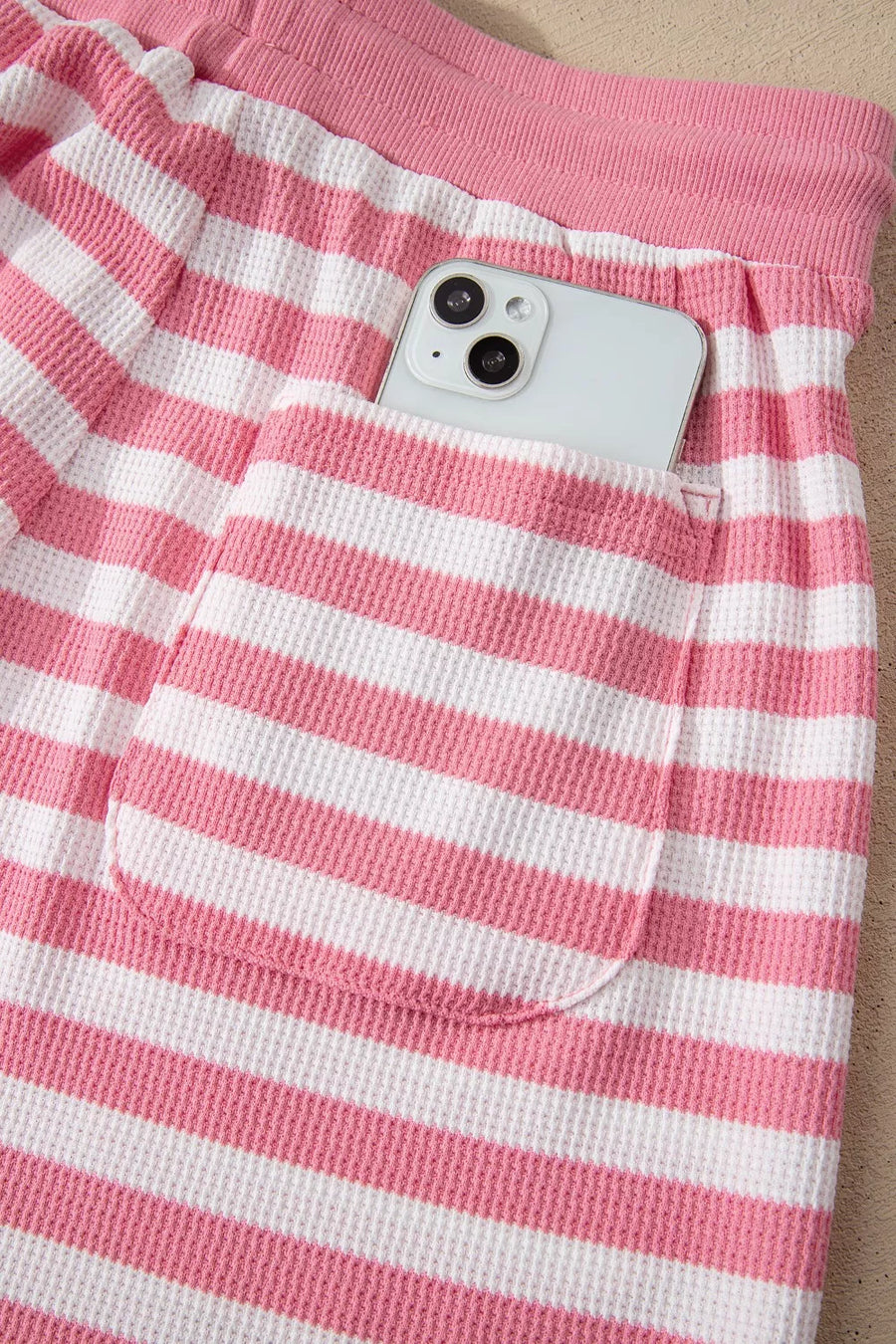Puffed sleeve striped two-piece ensemble in strawberry pink waffle knit with drawstring waist and pocket detail.