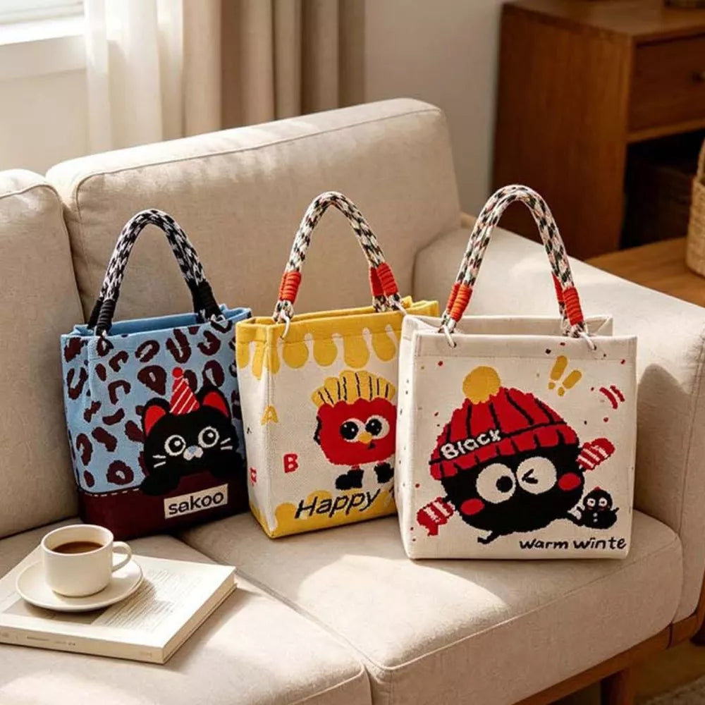 Cartoon graphic tote handbags in blue, yellow, and ivory with playful character designs.