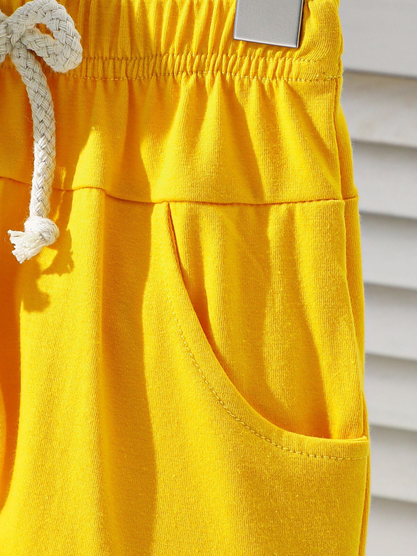 Yellow cotton baby shorts with drawstring and pocket detail