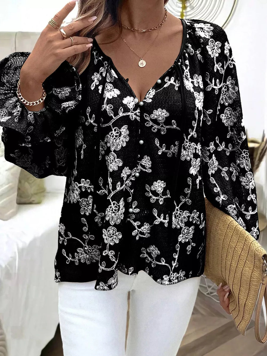 Black embroidered sheer long-sleeve blouse with button detail and floral pattern.