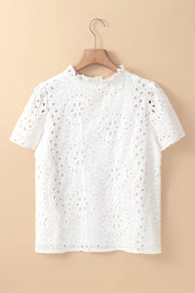 White embroidered eyelet blouse with short sleeves and ruffled mock neck.