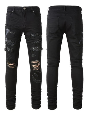Black skinny jeans with distressed rips and embroidered cobra detail.