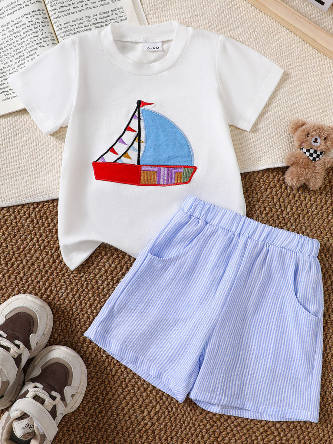 White baby tee with sailboat appliqué and blue striped shorts.