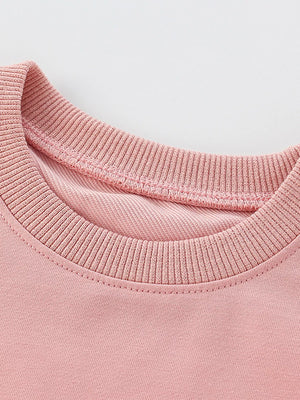 Pale blush cotton crew neck sweatshirt detail showing ribbed neckline and stitching.