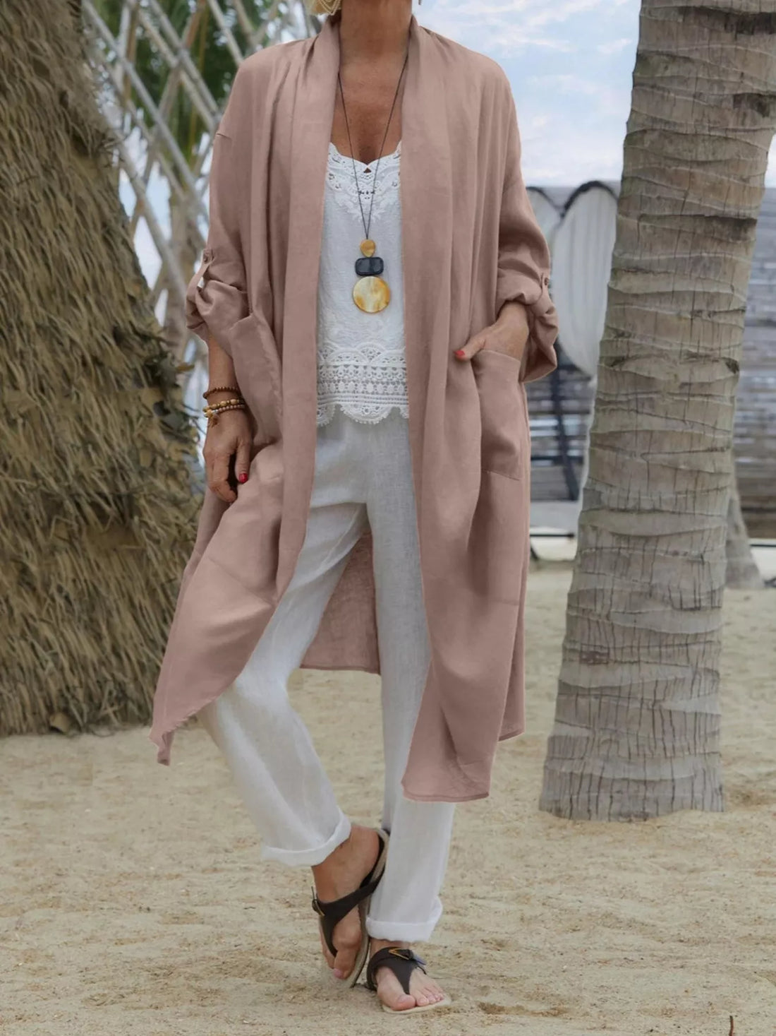Dusty pink lightweight open front cardigan with pockets, worn open over a white lace cami and white pants.