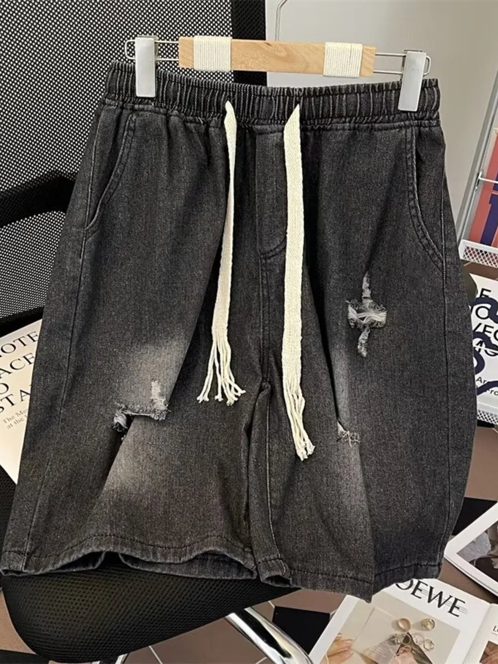 Black distressed denim shorts for men with drawstring waist and frayed details.