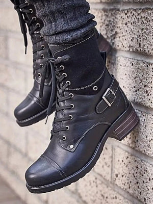 Black leather combat boots with contrast cuff, laces, buckle strap, and white stitching.