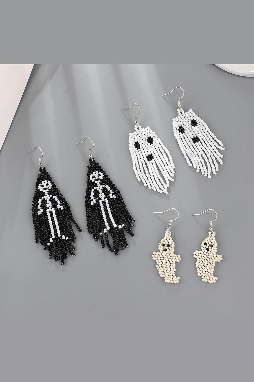 Beaded ghost and skeleton fringe earrings in ivory, black, and white.
