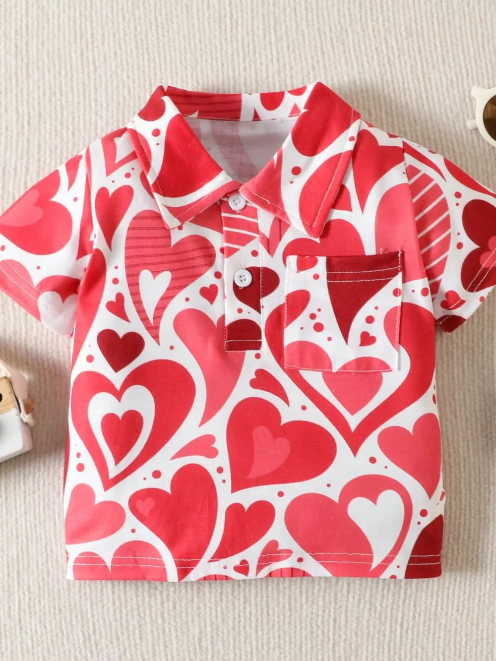 Red and white heart print cotton polo shirt with short sleeves and a chest pocket.
