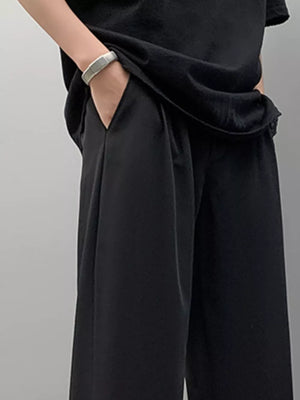 Men's black pleated casual pants with a relaxed fit and side pockets.