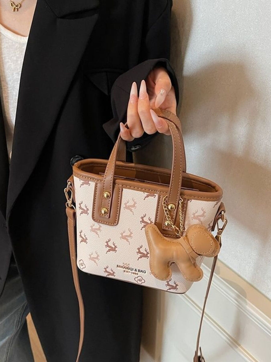 Charming mini crossbody bag in blush pink with deer print and dog charm.