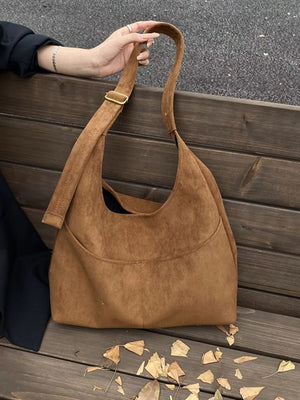 Large brown suede shoulder bag with adjustable strap and front pocket detail.
