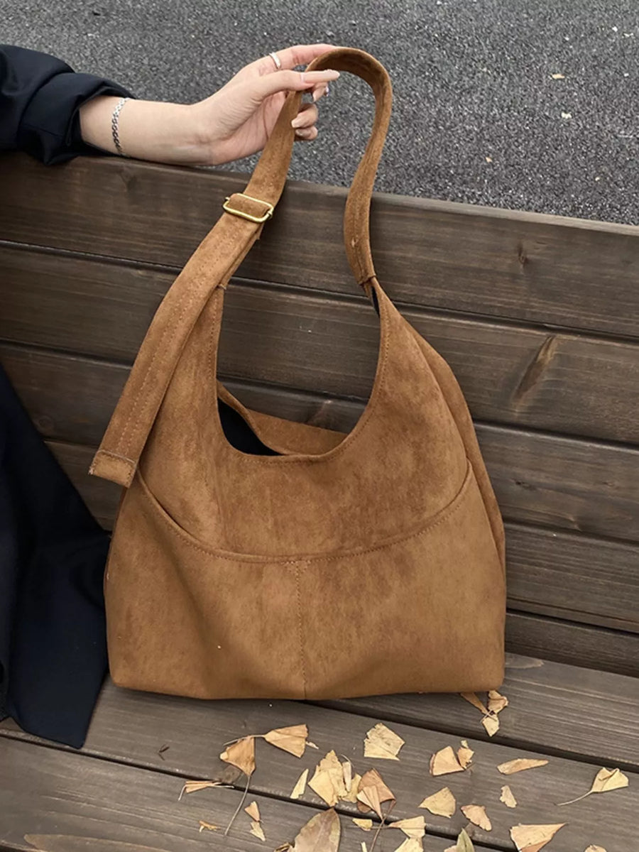Large brown suede shoulder bag with adjustable strap and front pocket detail.