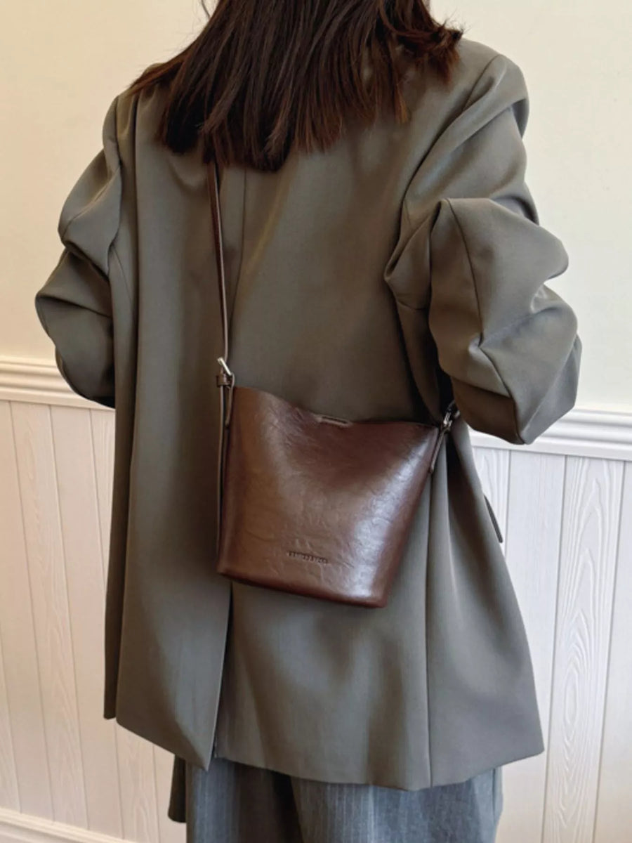 Chocolate leather bucket crossbody bag with a slouchy silhouette.
