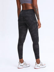 Black camouflage print performance leggings with pockets and reflective ankle detail.