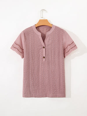 Pink eyelet embroidered short-sleeve blouse with button-up neckline and cutout details.