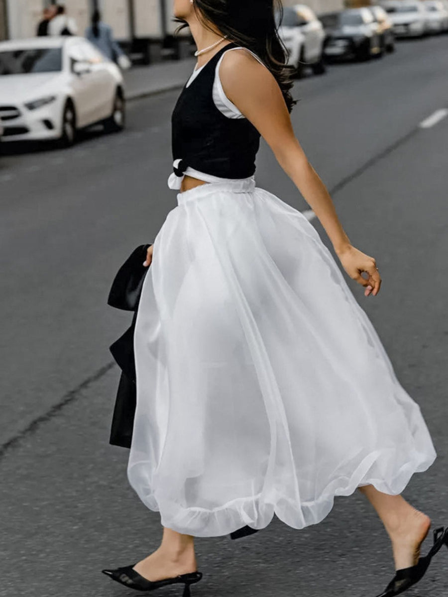 White midi skirt with sheer overlay and ruffled hem, worn with a black top.