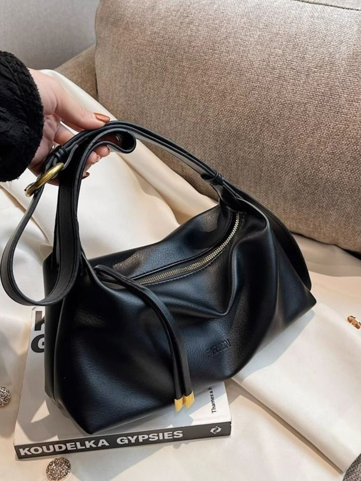 Black slouchy crossbody bag with adjustable strap and gold hardware detail.