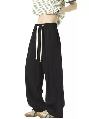 Men's black track pants with white drawstring and relaxed fit.