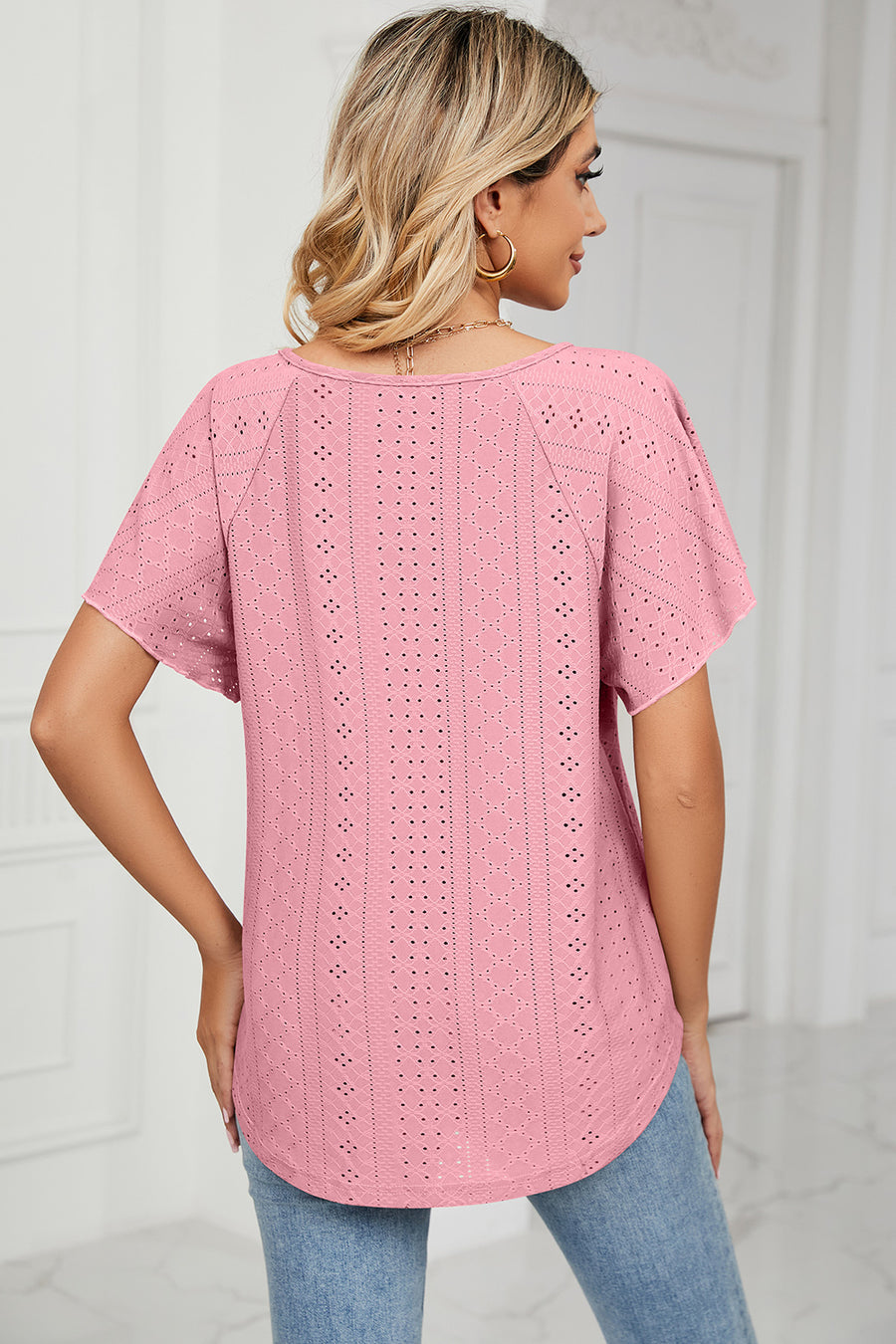Pink eyelet blouse with flutter sleeves and a tie-neck detail.