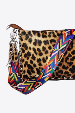 Leopard print shoulder bag with studded trim and colorful geometric strap.