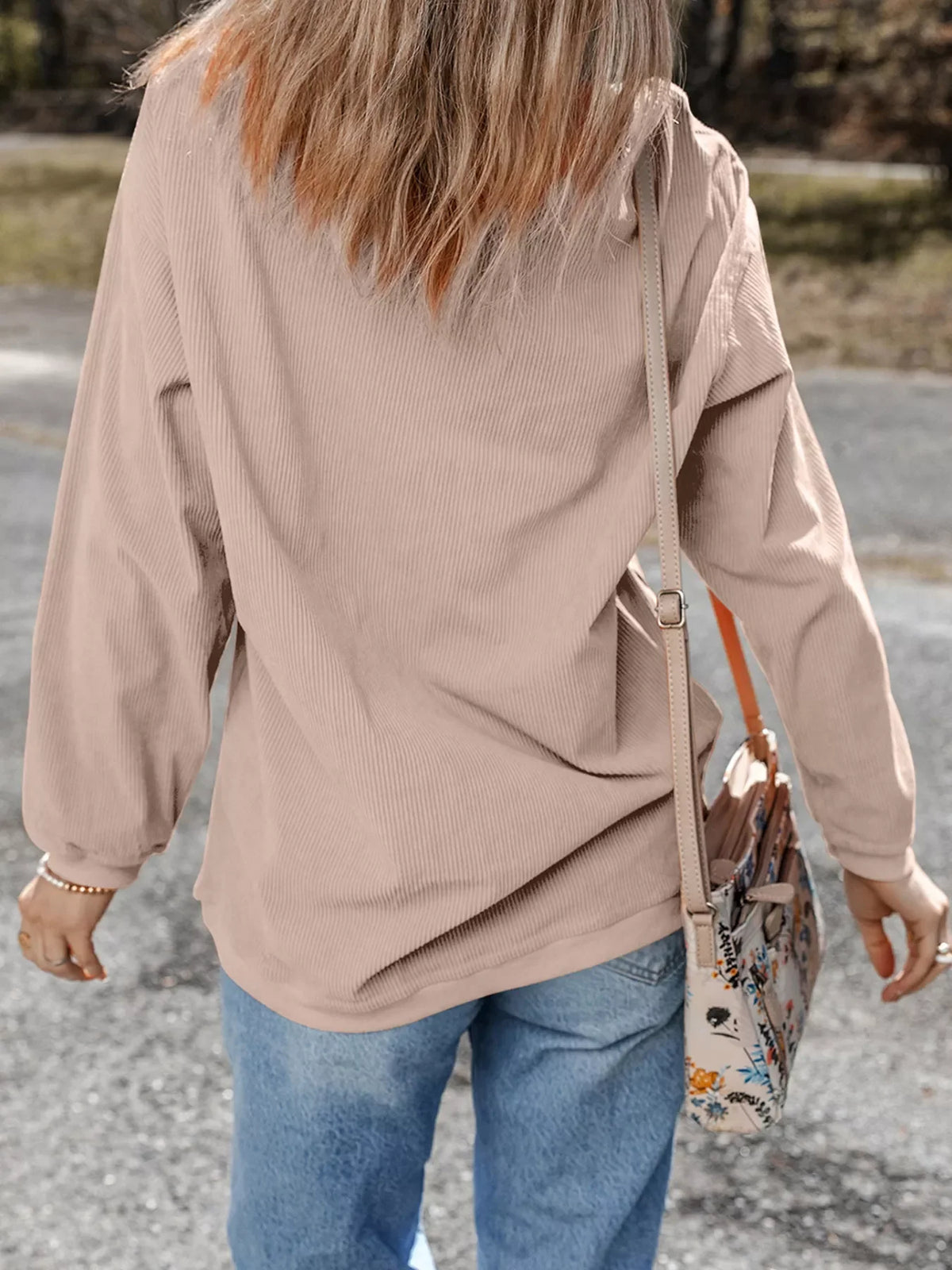 Eggshell corded sweatshirt with long sleeves, styled with jeans and a crossbody bag.