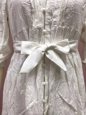 White embroidered cotton dress with a self-tie sash and button front.