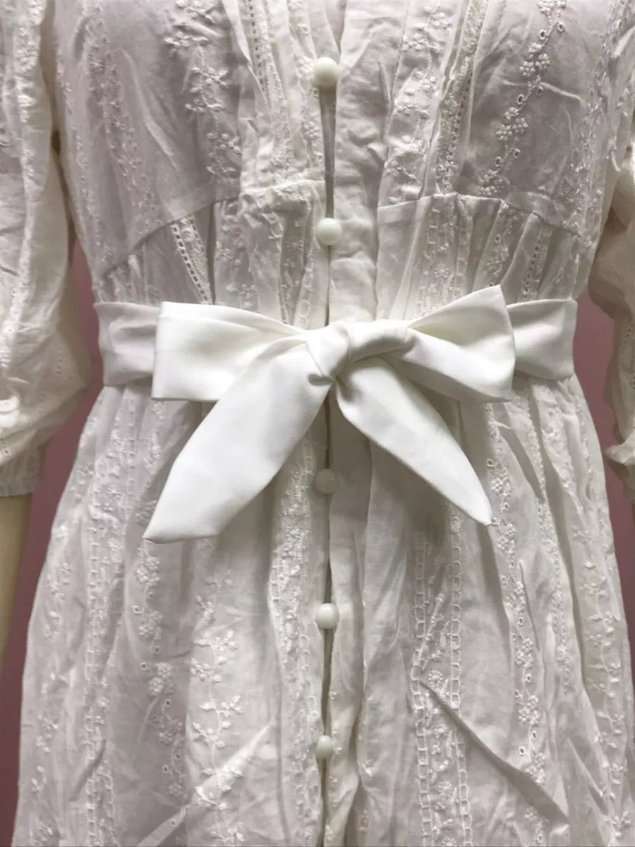 White embroidered cotton dress with a self-tie sash and button front.