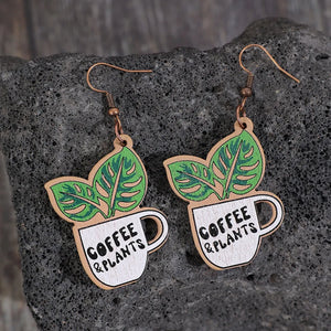 Coffee & Plants graphic drop earrings with green leaves and white cups.