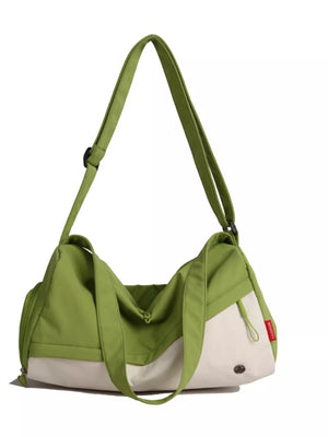 Color-block nylon travel bag in green and cream with adjustable strap and zipper closure.