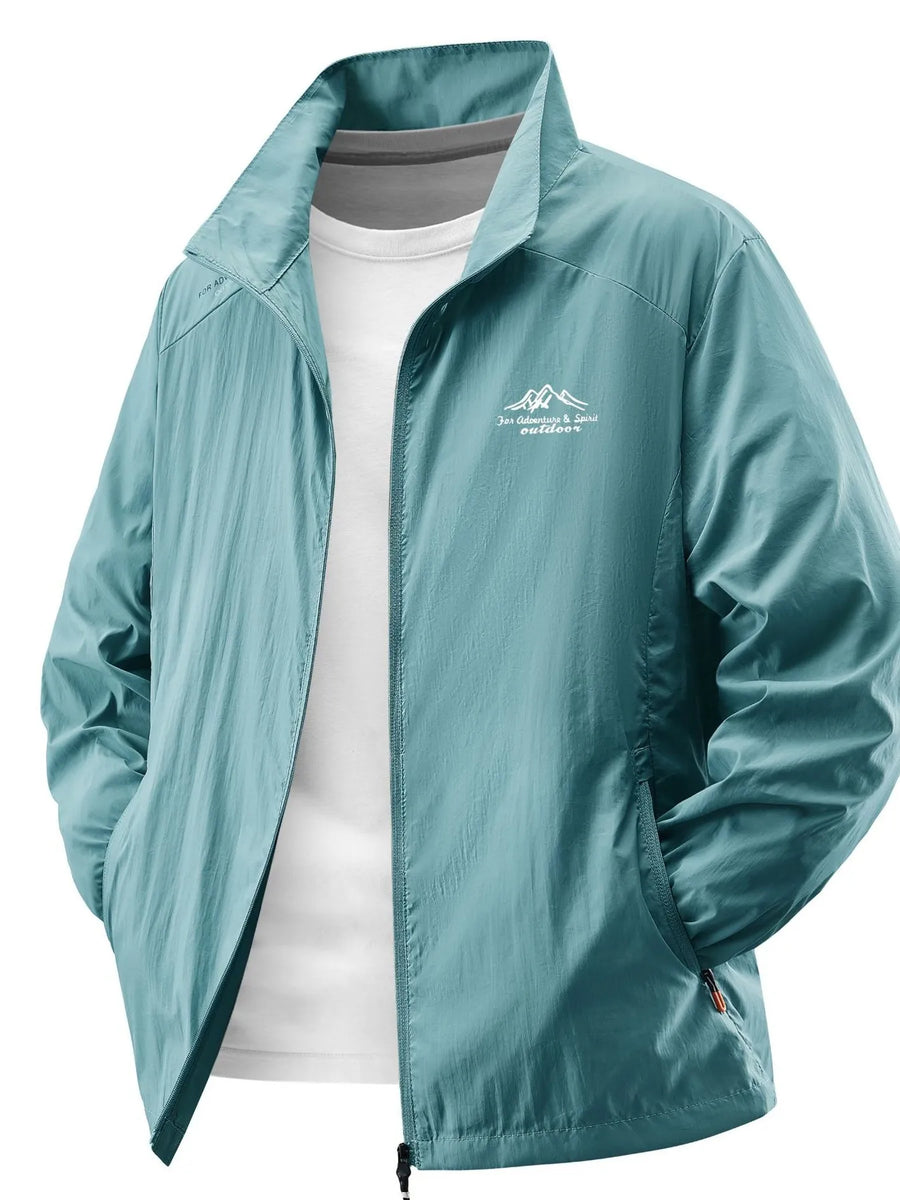 Lightweight windbreaker jacket in light blue with embroidered mountain logo and zip pockets.