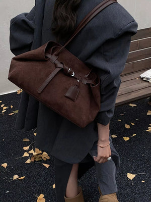 Women's brown suede shoulder bag with tie closure and leather details.