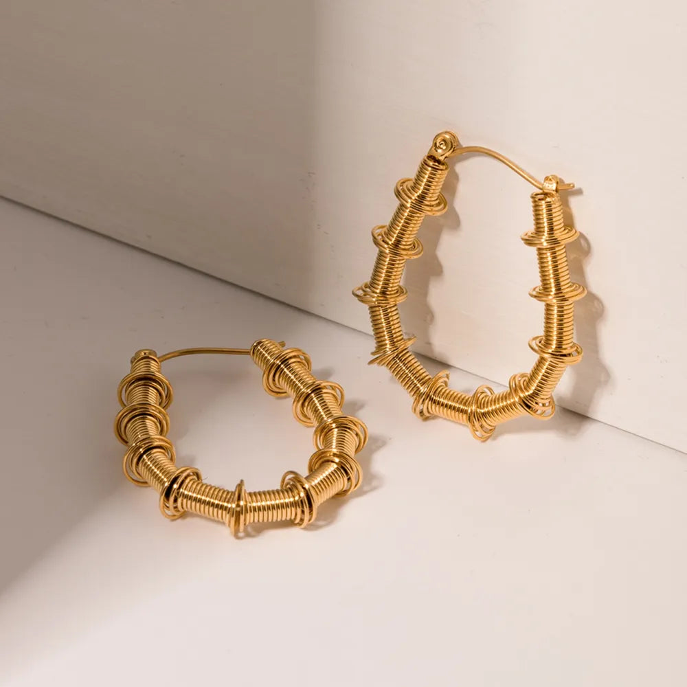 Gold coiled wire hoop earrings with textured details