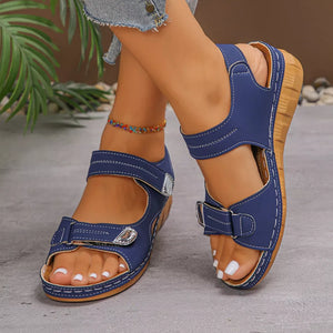 Dark blue adjustable wedge sandals with white stitching and buckle details.